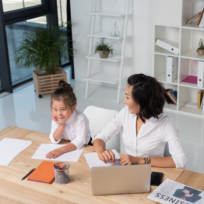 mother and child siting at desk together in front of laptop