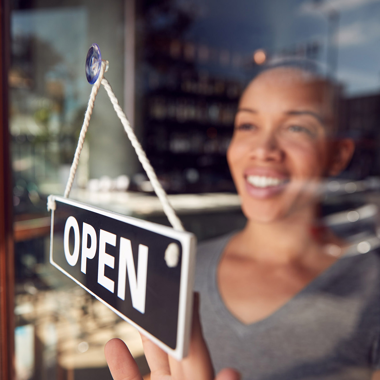 Female Owner Of Start Up Coffee Shop Or Restaurant Turning Round Open Sign On Door