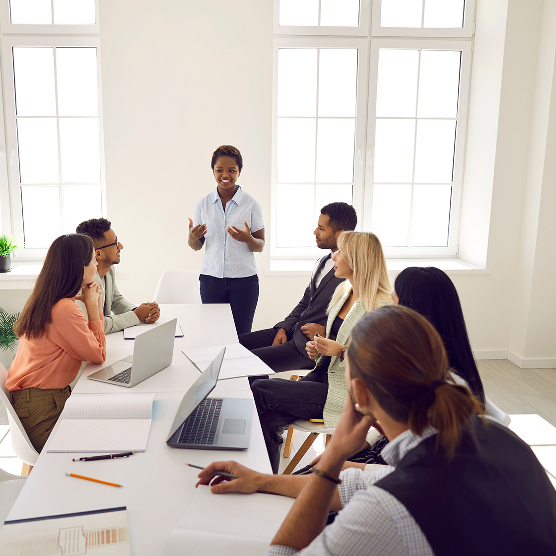Young smart business woman speaking to colleagues talking about investment and market strategies.